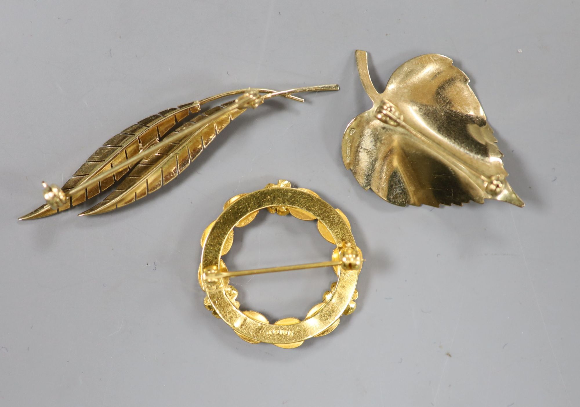 A 585 yellow metal double leaf brooch, 51mm a 9ct gold leaf brooch and a 10k tri-colour foliate wreath brooch (3)